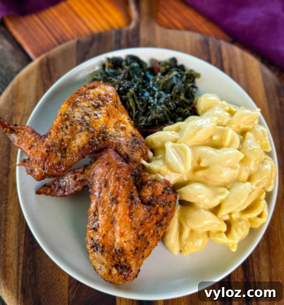 Plate with golden fried chicken wings, vibrant collard greens, and a generous serving of creamy stovetop mac and cheese