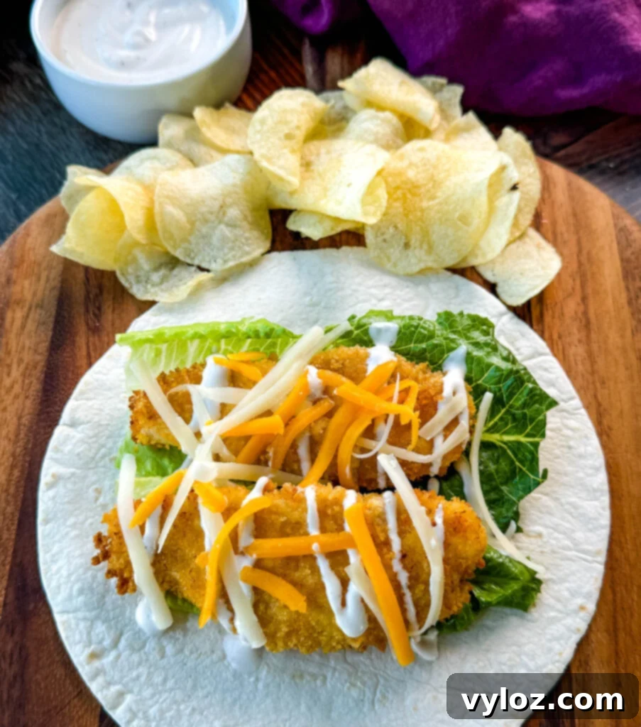 Homemade Chicken Snack Wraps 2 Crispy chicken snack wrap on a tortilla with ranch dressing, shredded cheese, and a side of chips