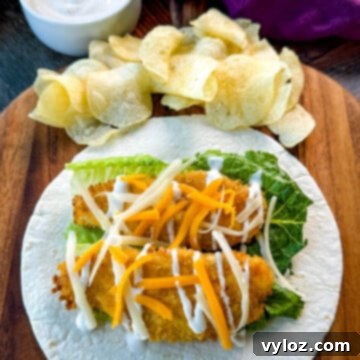 Homemade Chicken Snack Wraps 12 A delicious chicken snack wrap on a tortilla with ranch dressing and shredded cheese, served with a side of chips.