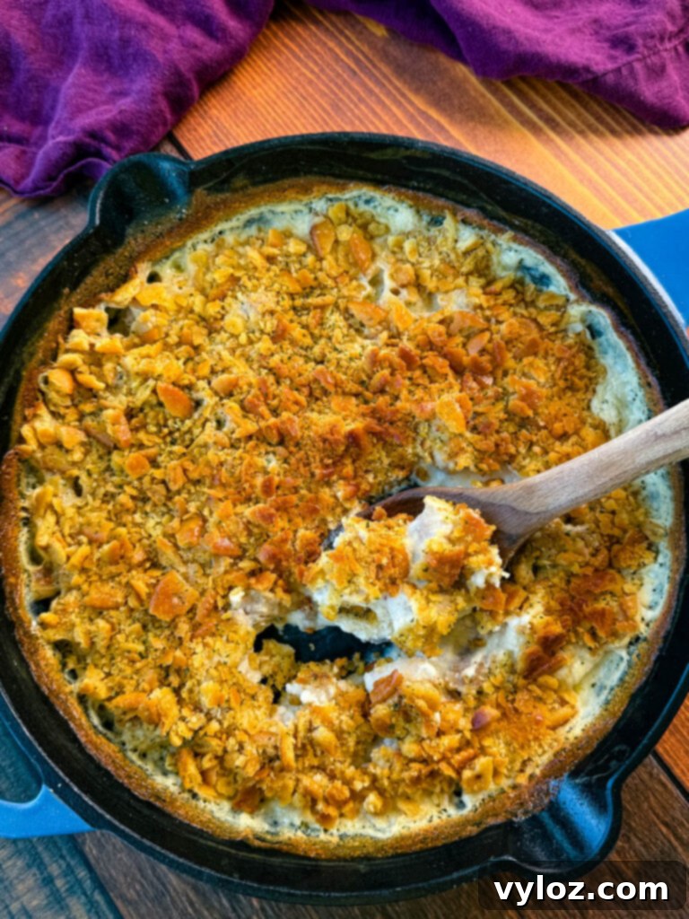 Million Dollar Chicken Bake 5 million dollar chicken casserole in a cast iron skillet with a wooden spoon