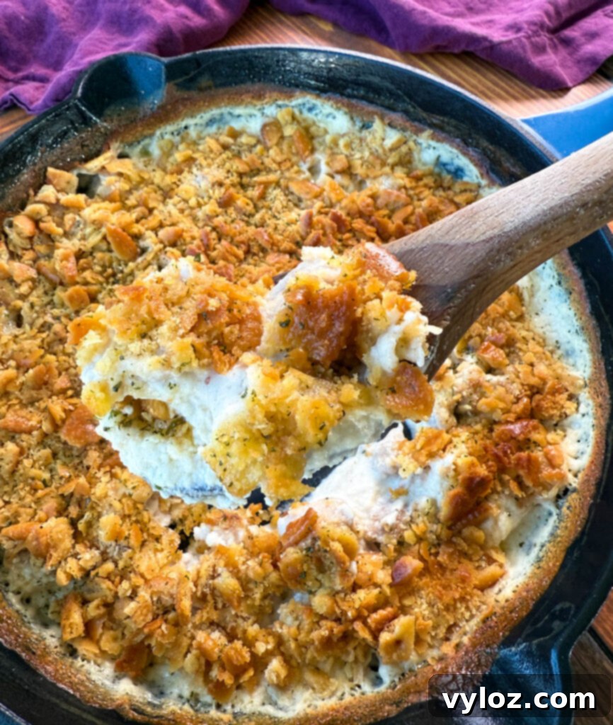 Million Dollar Chicken Bake 6 million dollar chicken casserole in a cast iron skillet with a wooden spoon