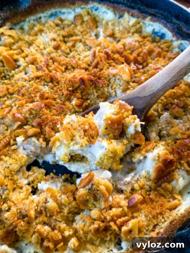 Million Dollar Chicken Bake 7 million dollar chicken casserole in a cast iron skillet with a wooden spoon