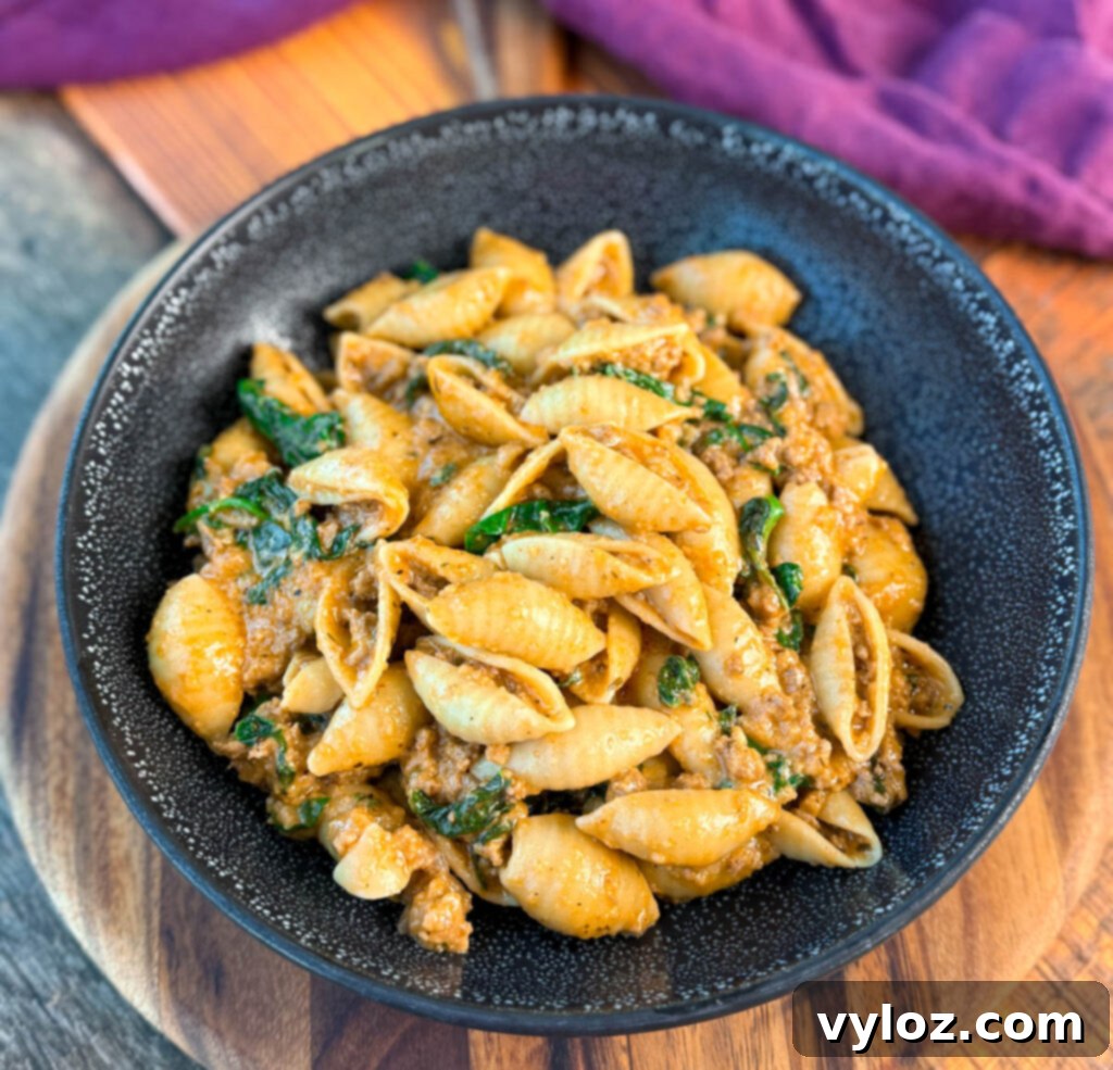 high protein beef and shells pasta with spinach in a black bowl