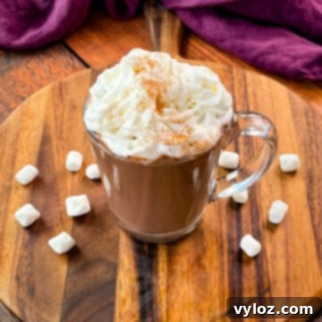 Creamy slow cooker Crockpot hot chocolate in a mug, topped with fluffy whipped cream and mini marshmallows.
