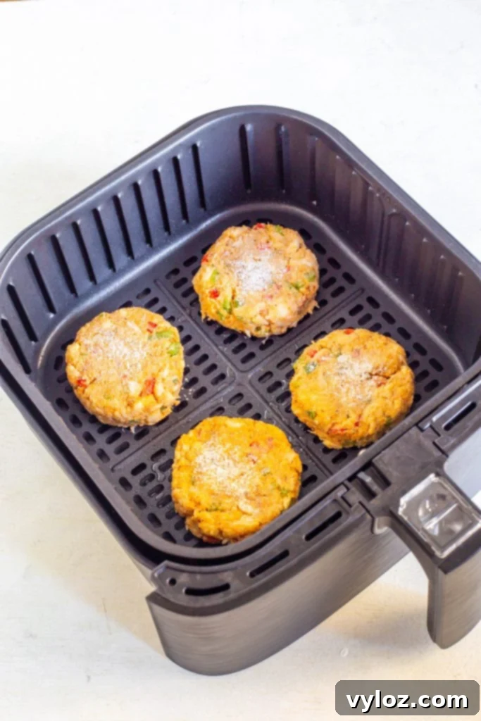 Quick and Crispy Air Fryer Crab Cakes 7 Close-up view of uncooked crab cakes resting in the air fryer basket, with a fine mist of cooking oil applied, ready for cooking