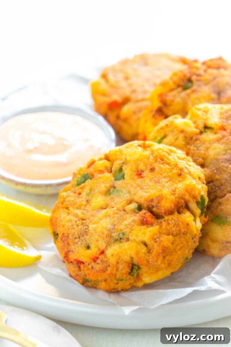 Quick and Crispy Air Fryer Crab Cakes 10 A close-up of a beautifully plated air-fried crab cake, adorned with a dollop of creamy sauce and a sprinkle of fresh green herbs, ready to be savored