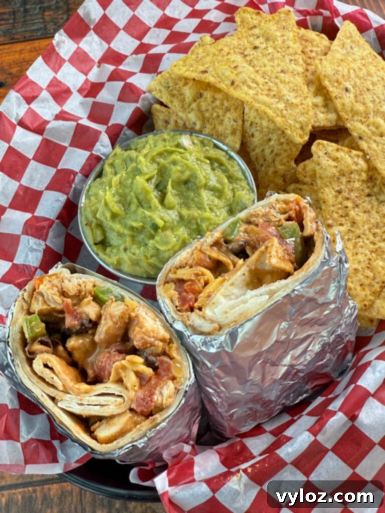 Ultimate Creamy Protein Chicken Burrito 11 Close-up of a high-protein chicken burrito, showing the filling, served with guacamole and chips