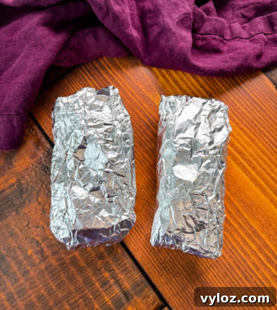 Ultimate Creamy Protein Chicken Burrito 8 Foil-wrapped high-protein chicken burritos on a flat surface, ready for storage or reheating