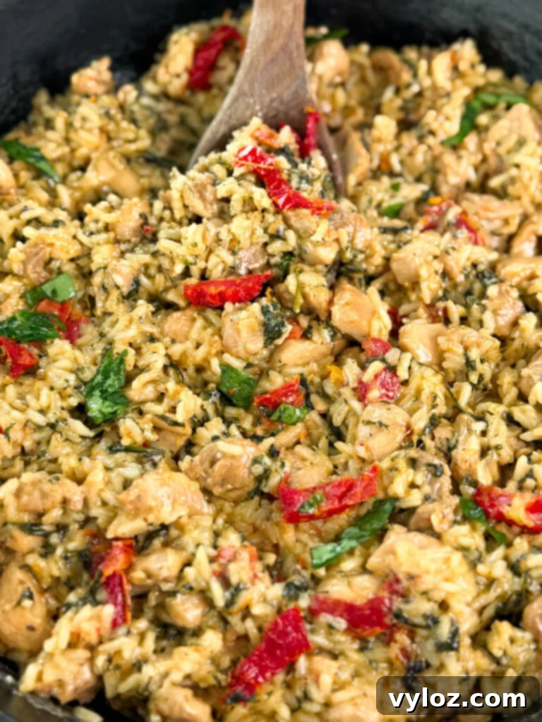 marry me chicken and rice in a pan with a wooden spoon