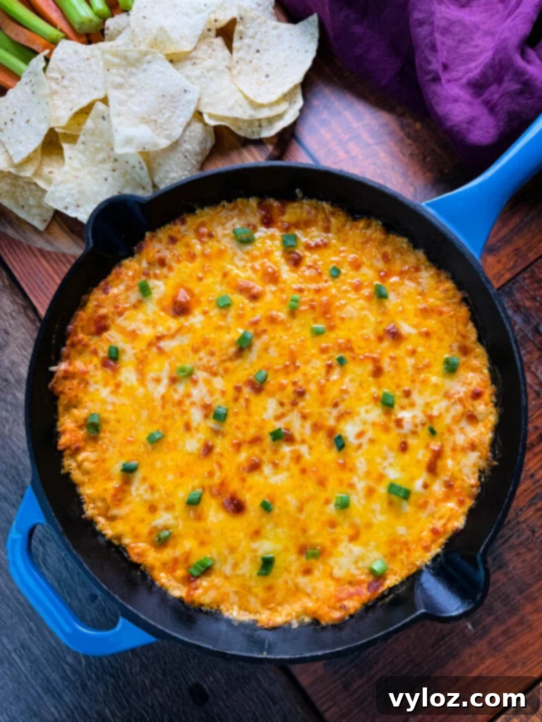 A spread of Buffalo Chicken Dip surrounded by tortilla chips, celery sticks, and carrot sticks, perfect for dipping.