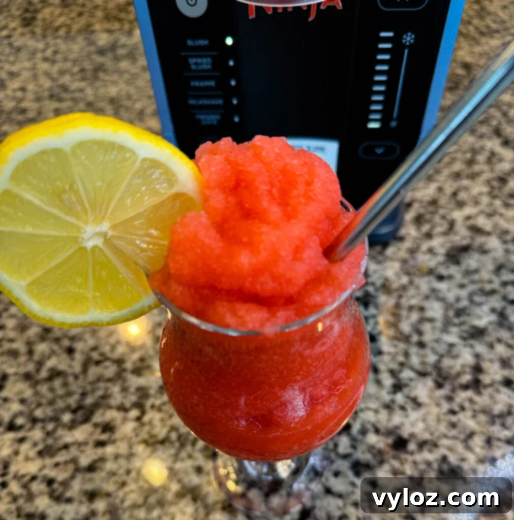 strawberry lemonade slushy in a glass with fresh lemon and a straw
