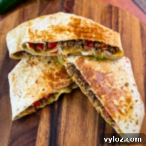 Golden brown beef and cheese crunchwrap supreme cut in half and stacked on a wooden cutting board with halved limes in the background.