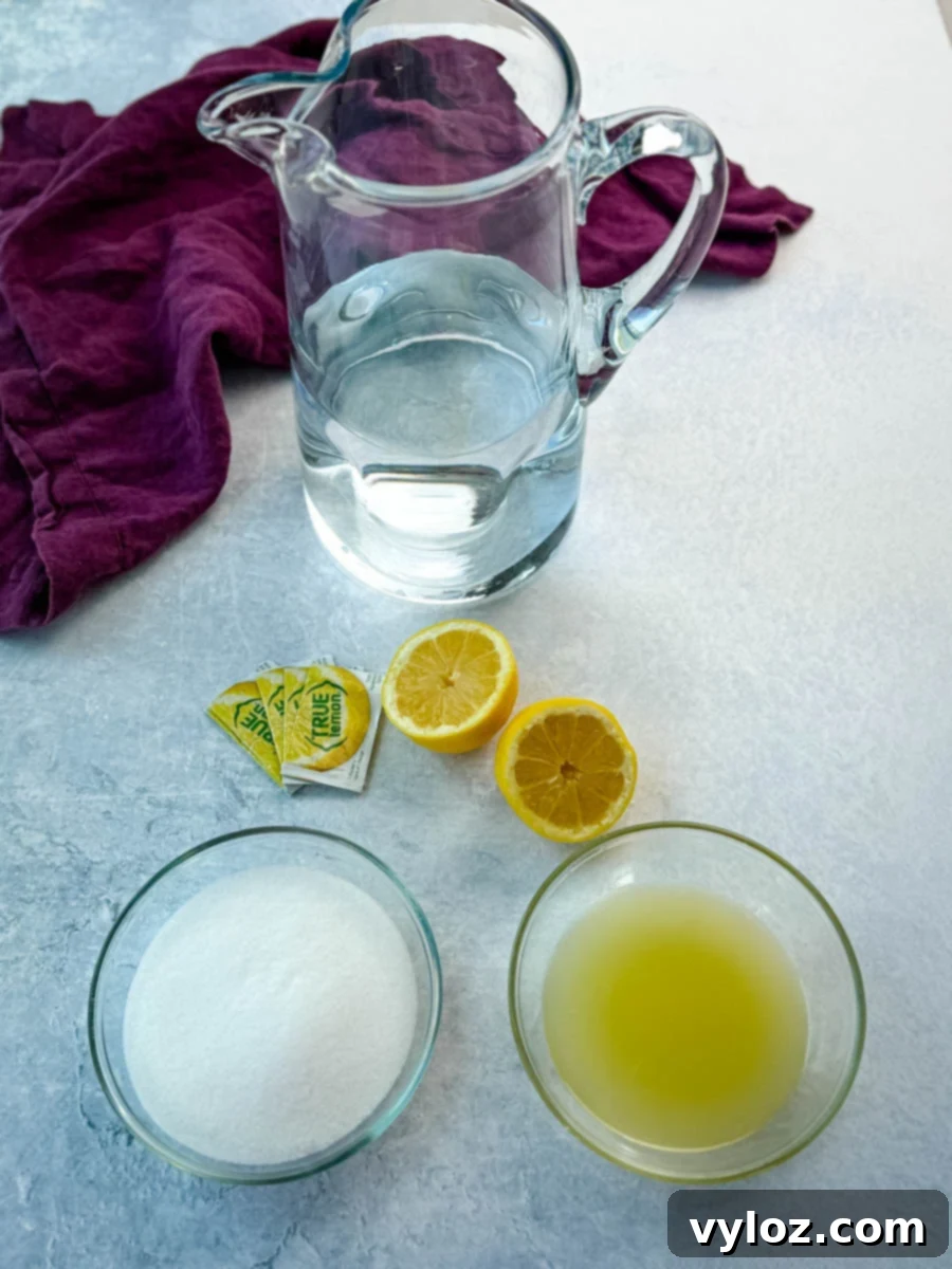 Ingredients for homemade lemonade displayed around an empty pitcher: a bowl of sugar, a bowl of lemon juice, lemon halves, lemon powder packets, and water, all arranged on a light surface with a purple napkin in the background.