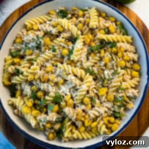 street corn pasta salad in a white bowl with cojita cheese, cilantro, and corn.