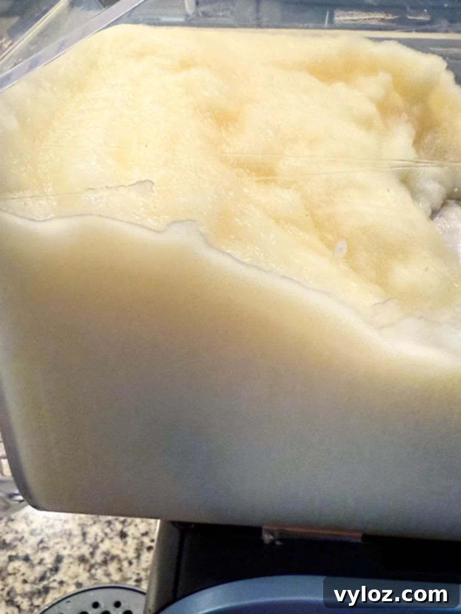 Large batch of piña colada slush inside the Ninja Slushi machine's container, ready for serving.