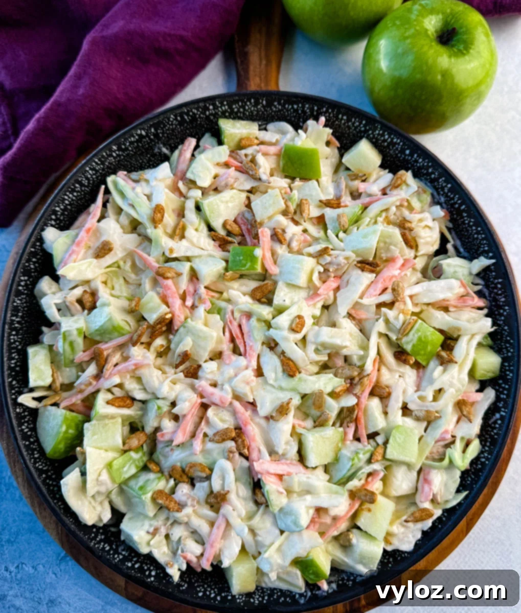Creamy Apple Crunch Slaw 5 Overhead angle of a black speckled bowl filled with creamy apple coleslaw and sprinkled with sunflower seeds.