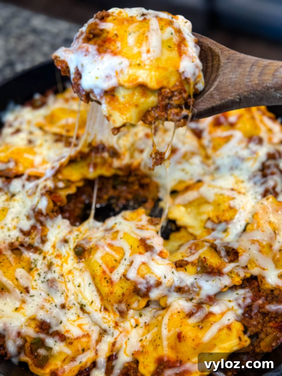 Dramatic close-up of a gooey, cheesy scoop of ravioli lasagna being lifted from the skillet, with melted cheese stretching from the pan.