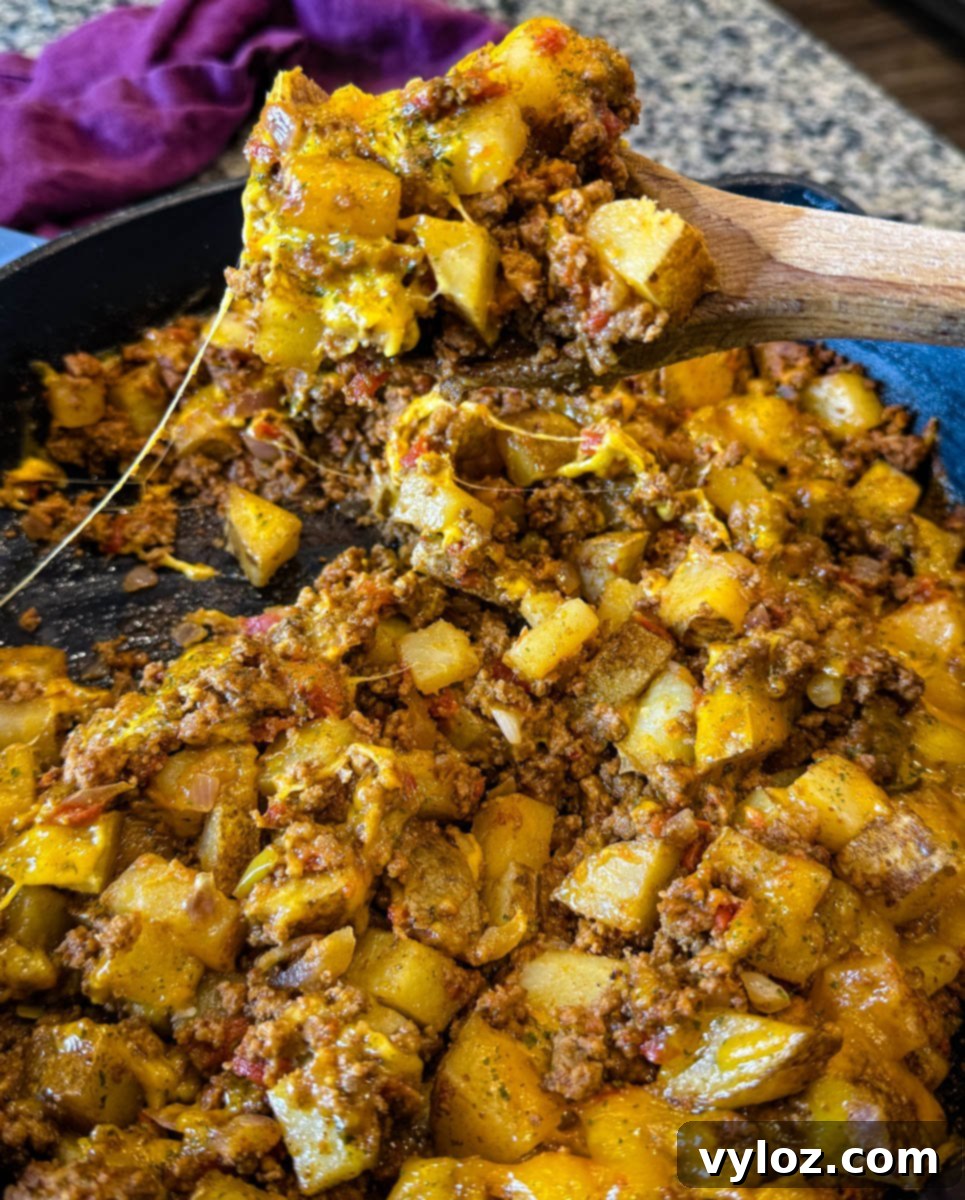 Savory Taco Potatoes 10 Close-up of a wooden spoon scooping cheesy taco potato mixture straight from a hot skillet—melted cheese and savory filling in every bite.