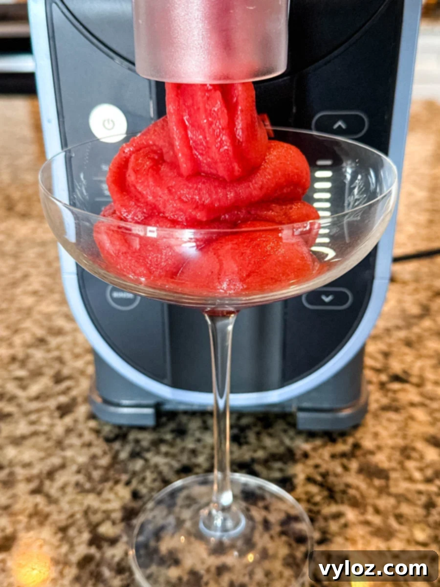 Frosé being dispensed directly into a cocktail glass from the Ninja Slushi machine, showing the machine in use.