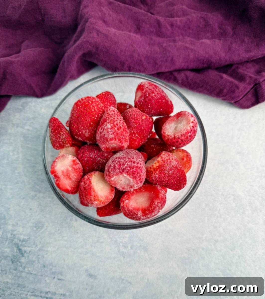 Ninja Slushi Strawberry Burst 3 frozen strawberries in a glass bowl