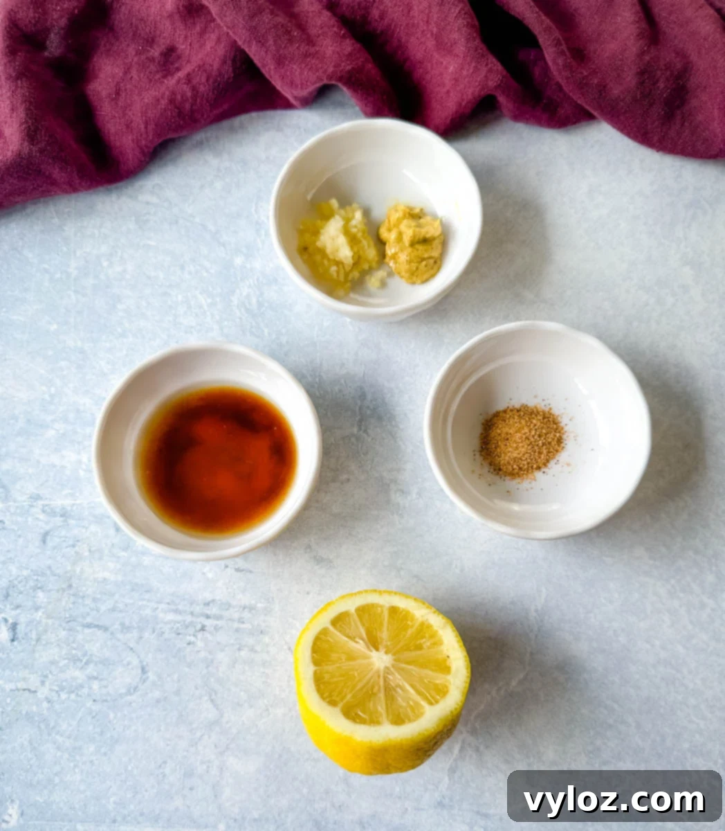 Easy Homemade Remoulade 3 Flat lay of individual remoulade sauce ingredients in small white bowls, including Dijon mustard, minced garlic, hot sauce, Creole seasoning, and a halved lemon, set against a light blue background.