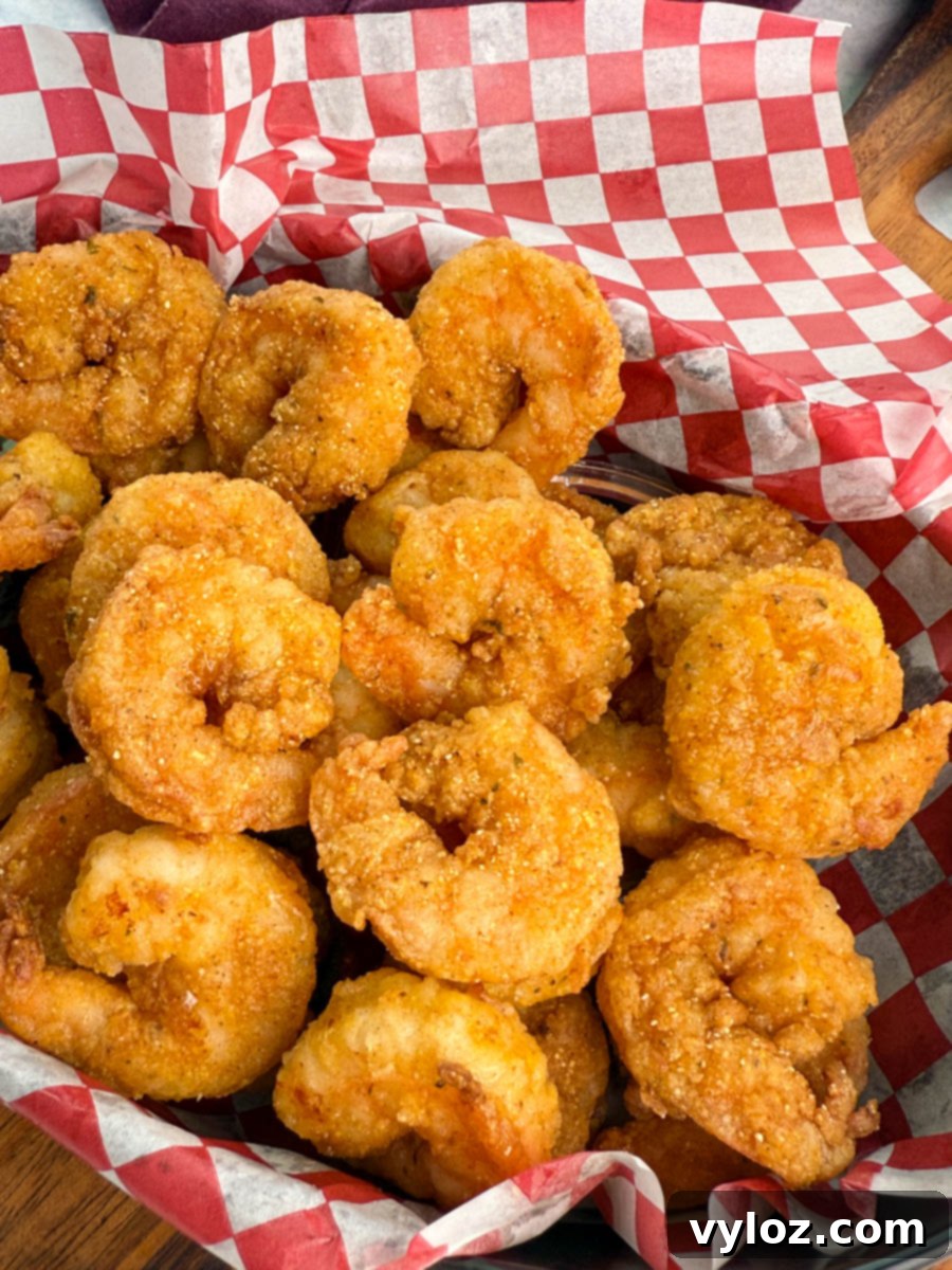 Close-up of a basket filled with well-seasoned, crispy fried shrimp, showcasing golden brown color and cornmeal coating.