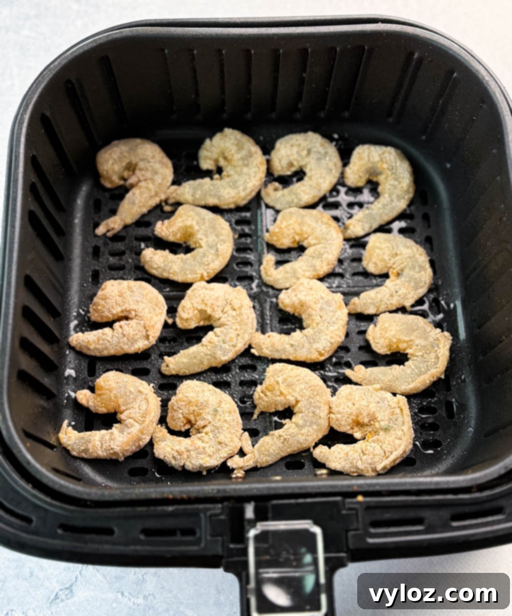Raw breaded shrimp arranged neatly in an air fryer basket before cooking.