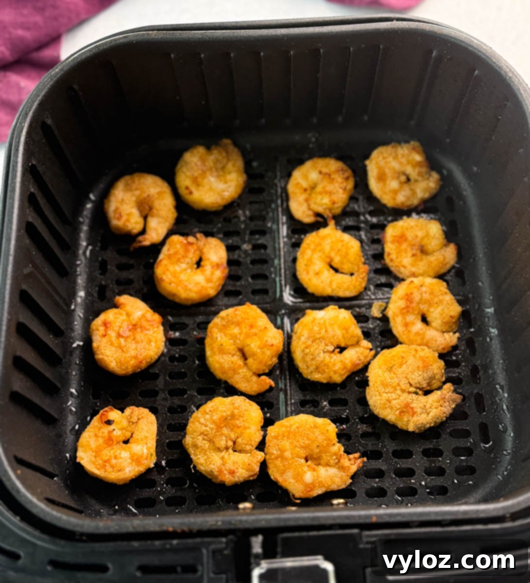 Golden breaded shrimp arranged inside an air fryer basket, freshly cooked and ready to serve.