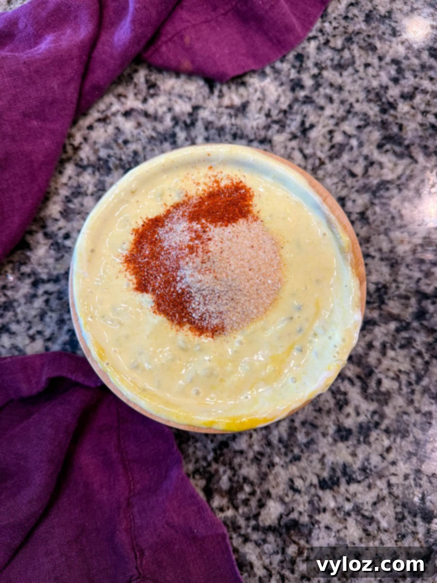 Top-down view of a bowl of freshly made Big Mac sauce, with a vibrant sprinkle of paprika, garlic powder, and onion powder on top, resting beside a soft purple napkin.