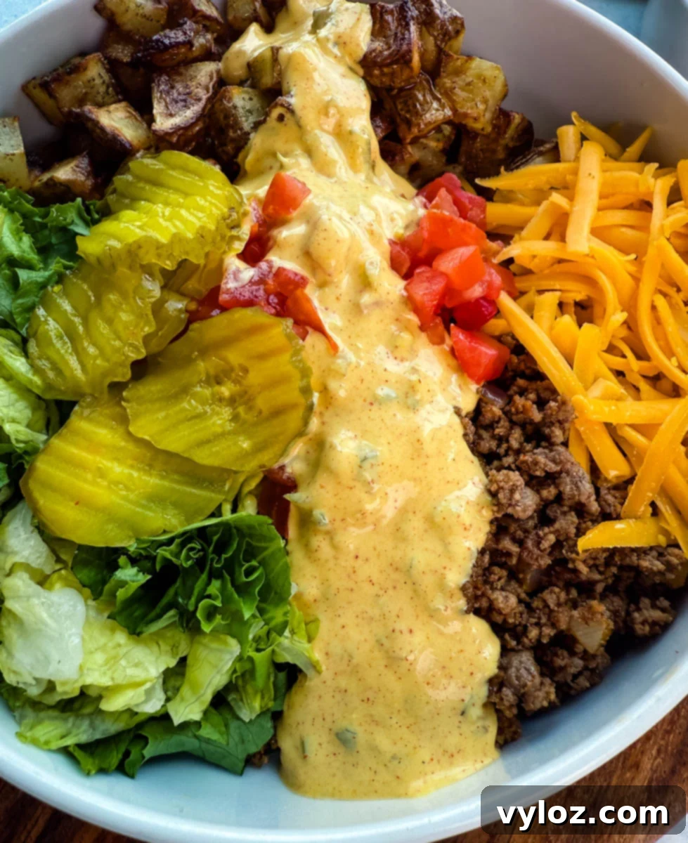 Zoomed-in shot of a Big Mac bowl highlighting each layer: golden roasted potatoes, fresh lettuce, pickles, chopped tomatoes, ground beef, shredded cheddar cheese, and Big Mac sauce drizzled down the center.