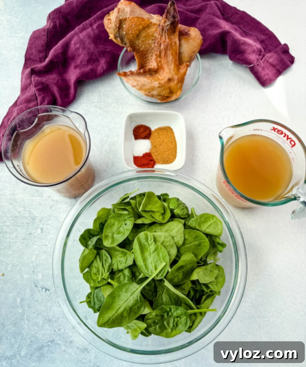 Bowls of fresh spinach, smoked turkey wing, chicken broth, spices, and seasonings arranged on a counter.
