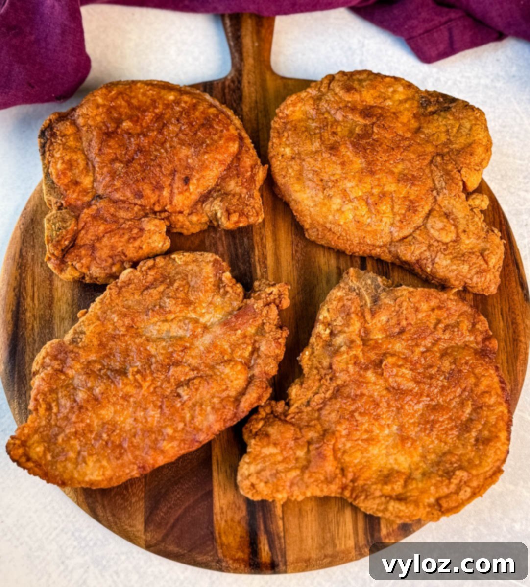 Crispy Southern Fried Pork Chops 2 Close-up of golden fried pork chops with a crunchy coating arranged on a cutting board.