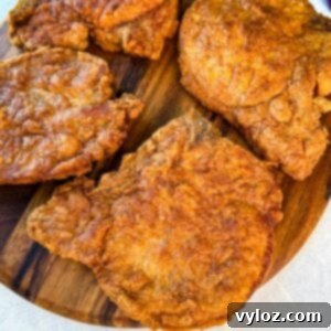 Crispy Southern Fried Pork Chops 13 Close-up of golden fried pork chops with a crunchy coating arranged on a cutting board.