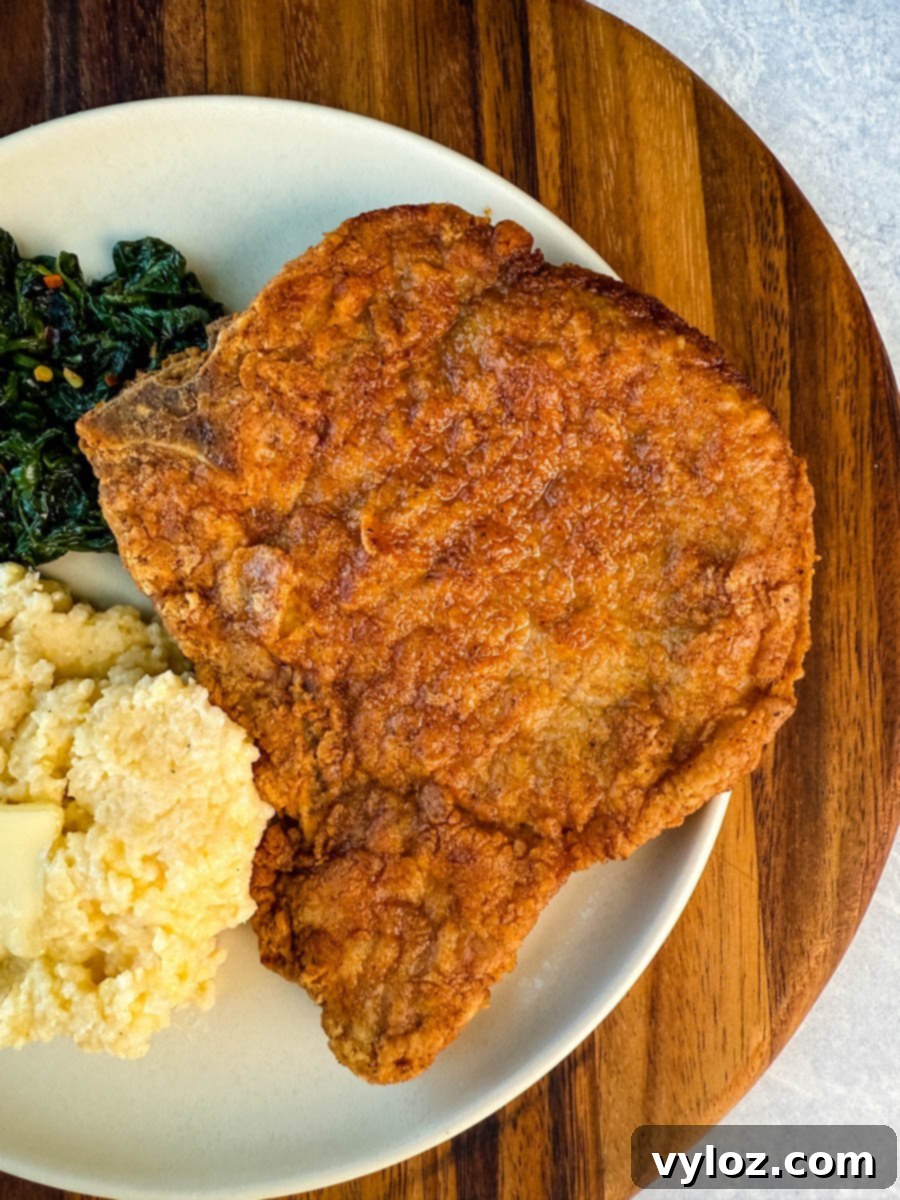 Crispy Southern Fried Pork Chops 14 A beautifully plated Southern meal featuring fried pork chops, grits, and collard greens.