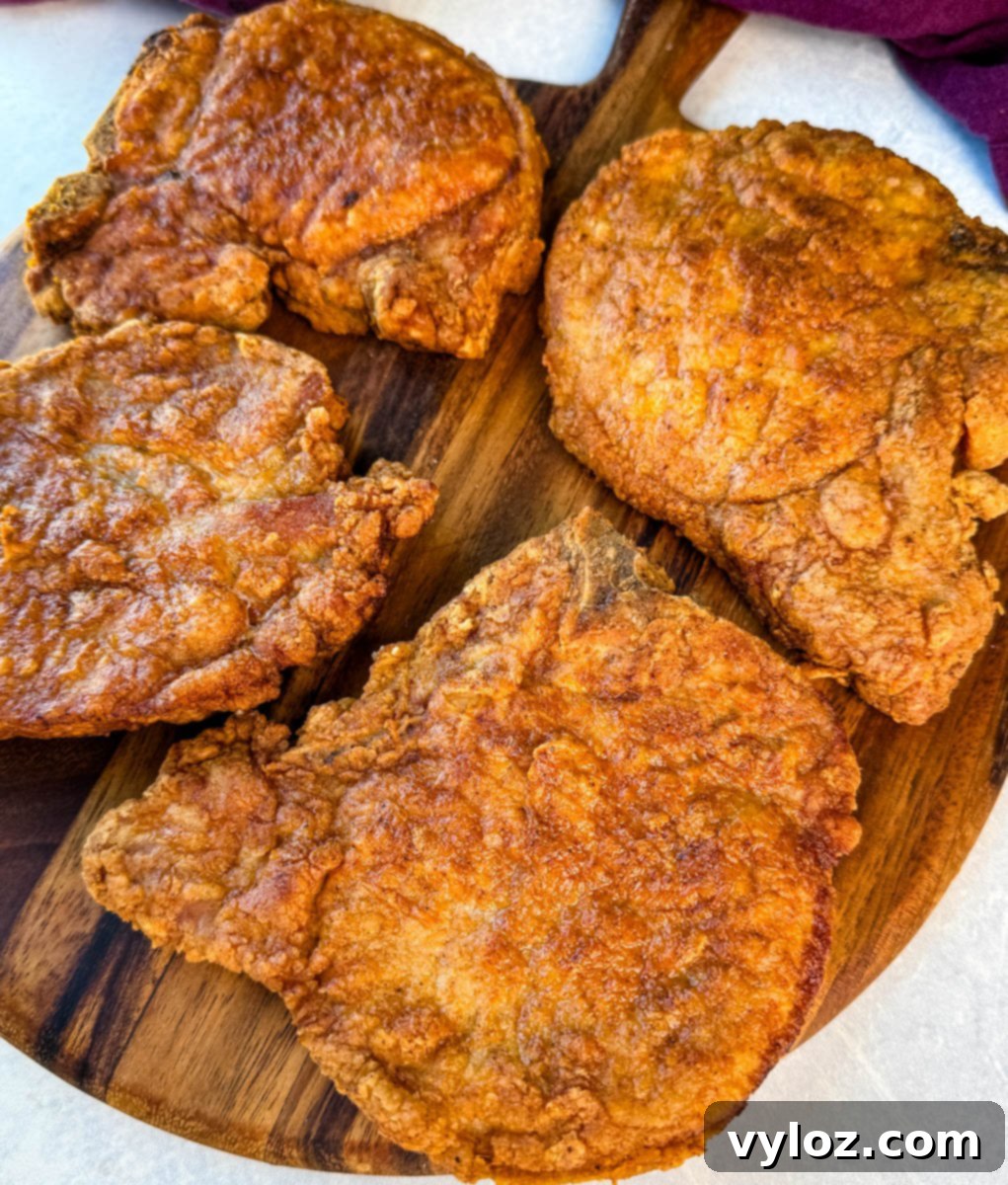 Crispy Southern Fried Pork Chops 15 Close-up of golden fried pork chops with a crunchy coating arranged on a cutting board, ready to be served.