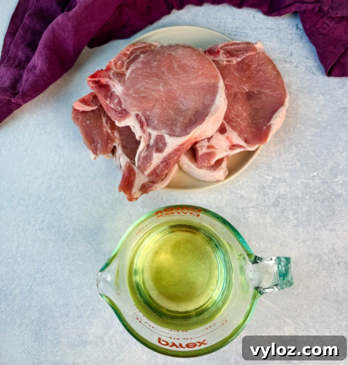Crispy Southern Fried Pork Chops 6 A plate of raw bone-in pork chops next to a measuring cup filled with oil, prepped for frying.