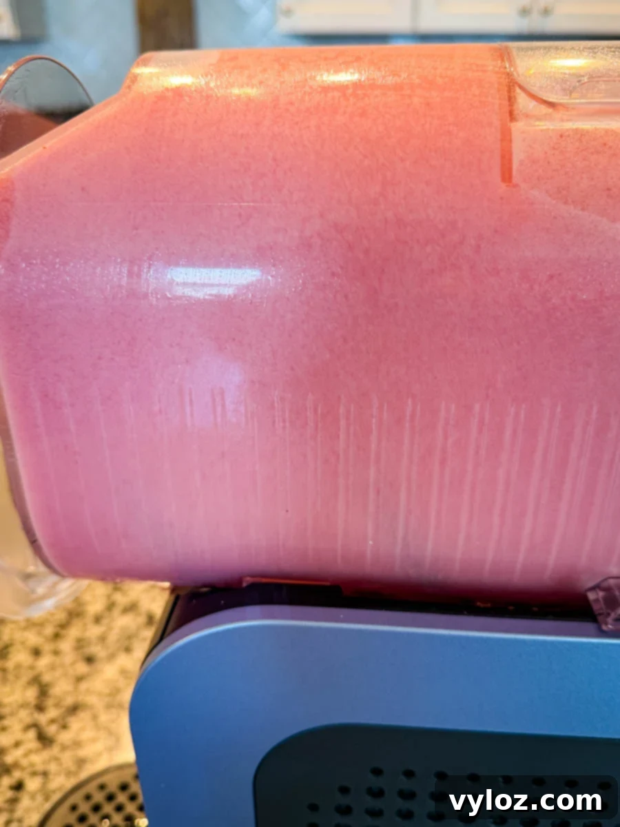 Another angle of the blended pink slush inside the Ninja Slushi machine, showing the fluffy texture against the container walls.