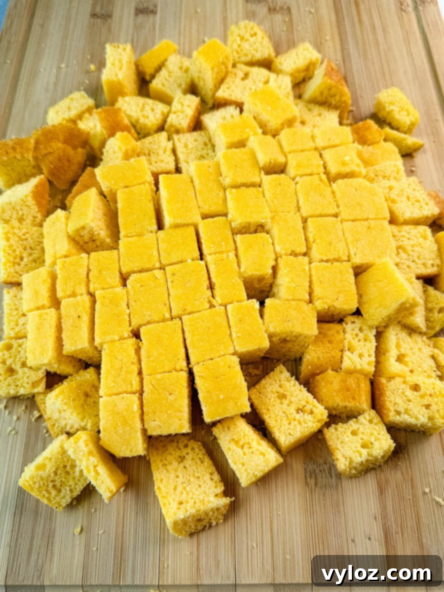 Close-up view of golden Southern cornbread cubes, freshly cut and piled, displaying their perfect texture and readiness to be incorporated as a key layer in the vibrant salad.