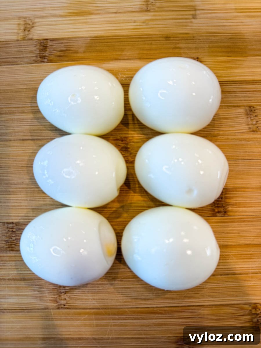 Homestyle Southern Deviled Eggs 6 Six peeled hard-boiled eggs on a wooden cutting board.