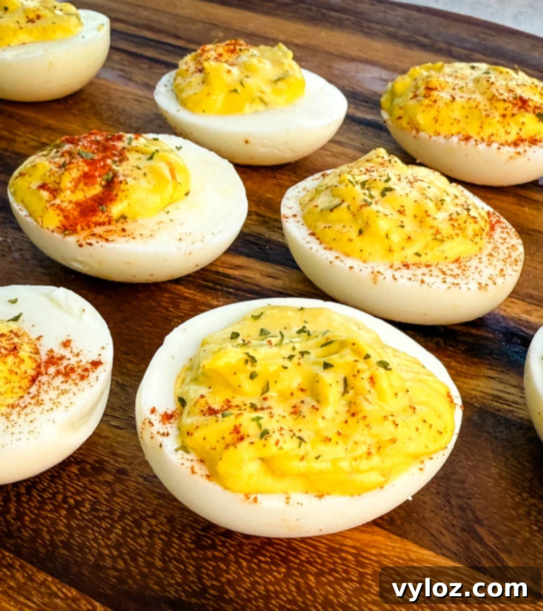 Homestyle Southern Deviled Eggs 9 Deviled eggs on a wooden board with paprika and parsley garnish, close-up of creamy filling texture.