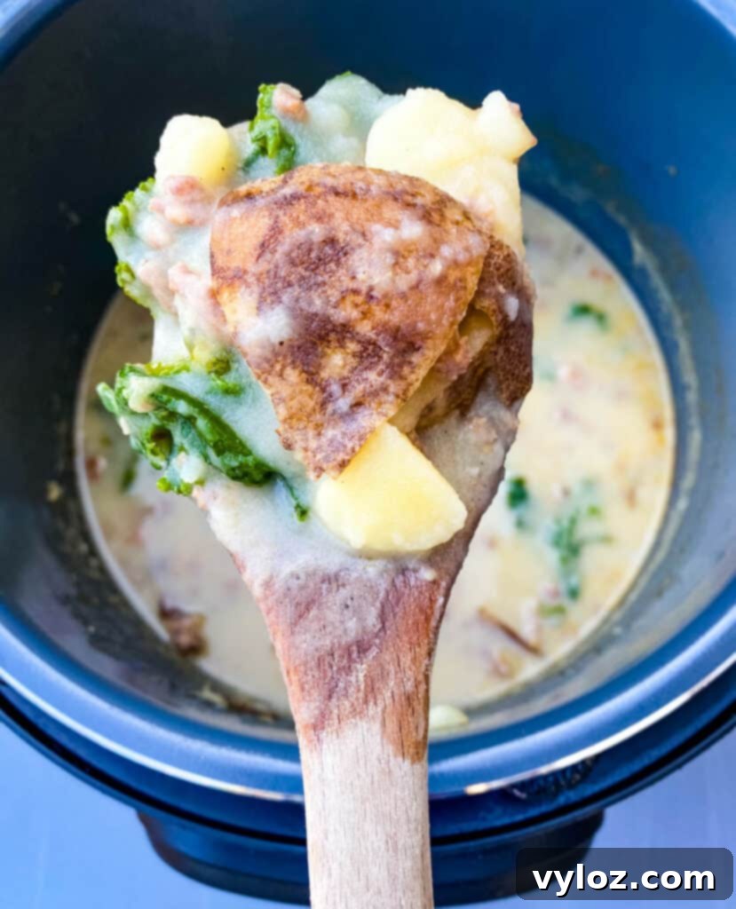 A wooden spoon serving a scoop of creamy Instant Pot Zuppa Toscana soup