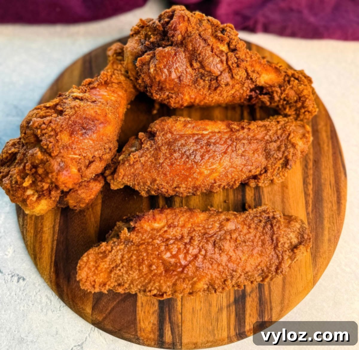 Four crispy fried turkey wings arranged on a wooden serving board, showcasing their crunchy, golden coating.
