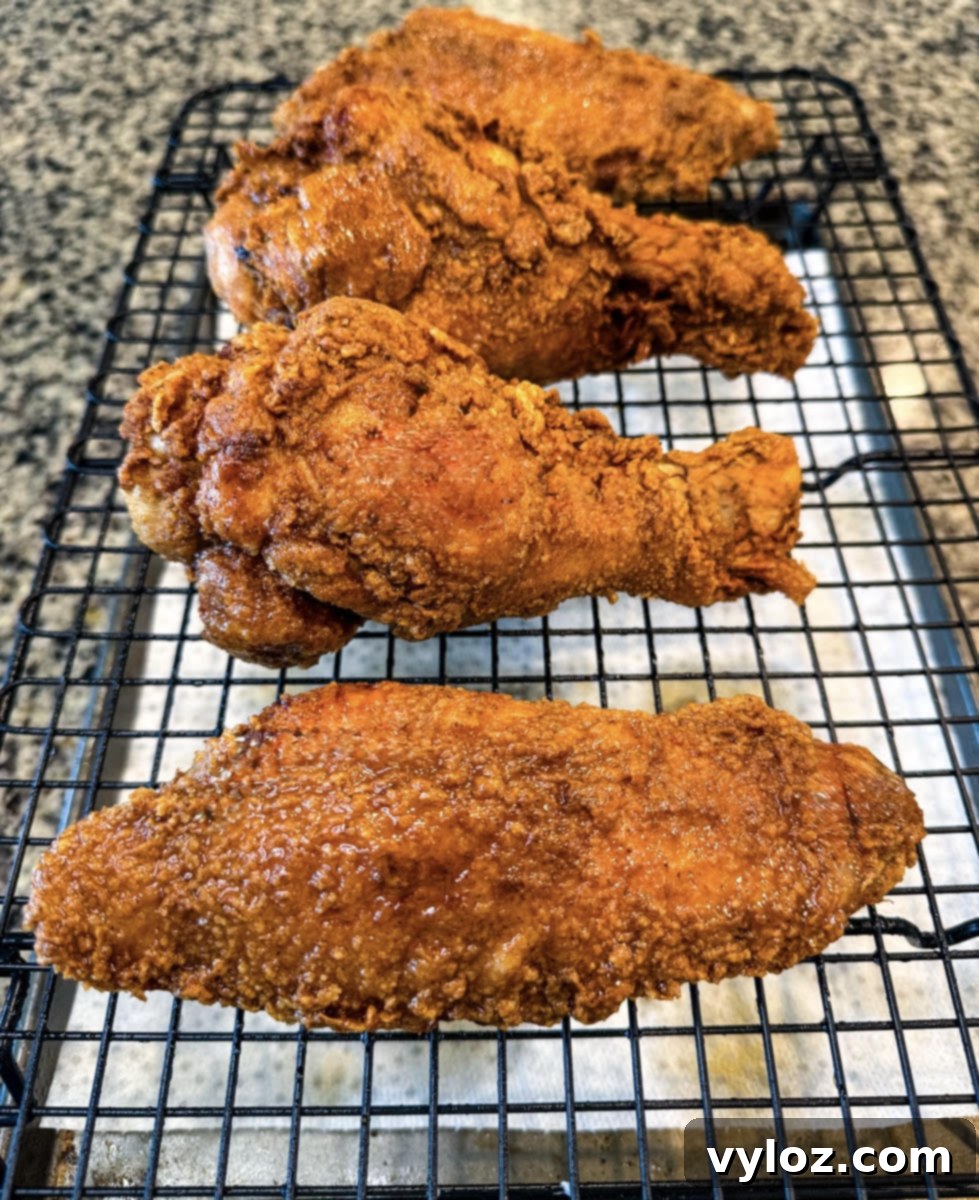 Side view of crispy fried turkey wings on a wire rack lined with paper towels to absorb excess oil.