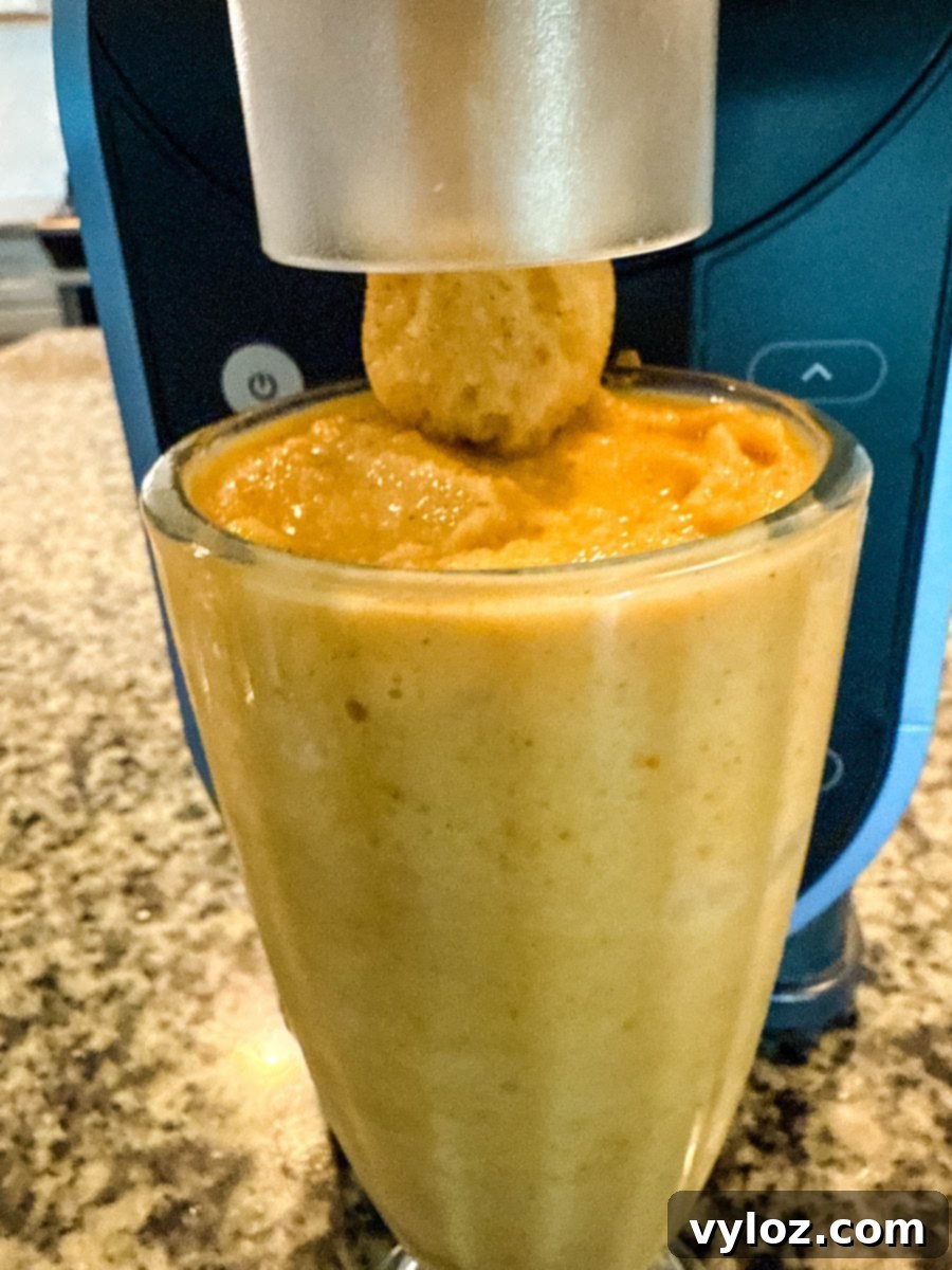 Ninja Slushi's Autumn Spice Elixir 6 Pumpkin spice milkshake being dispensed from the Ninja Slushi machine directly into a glass.