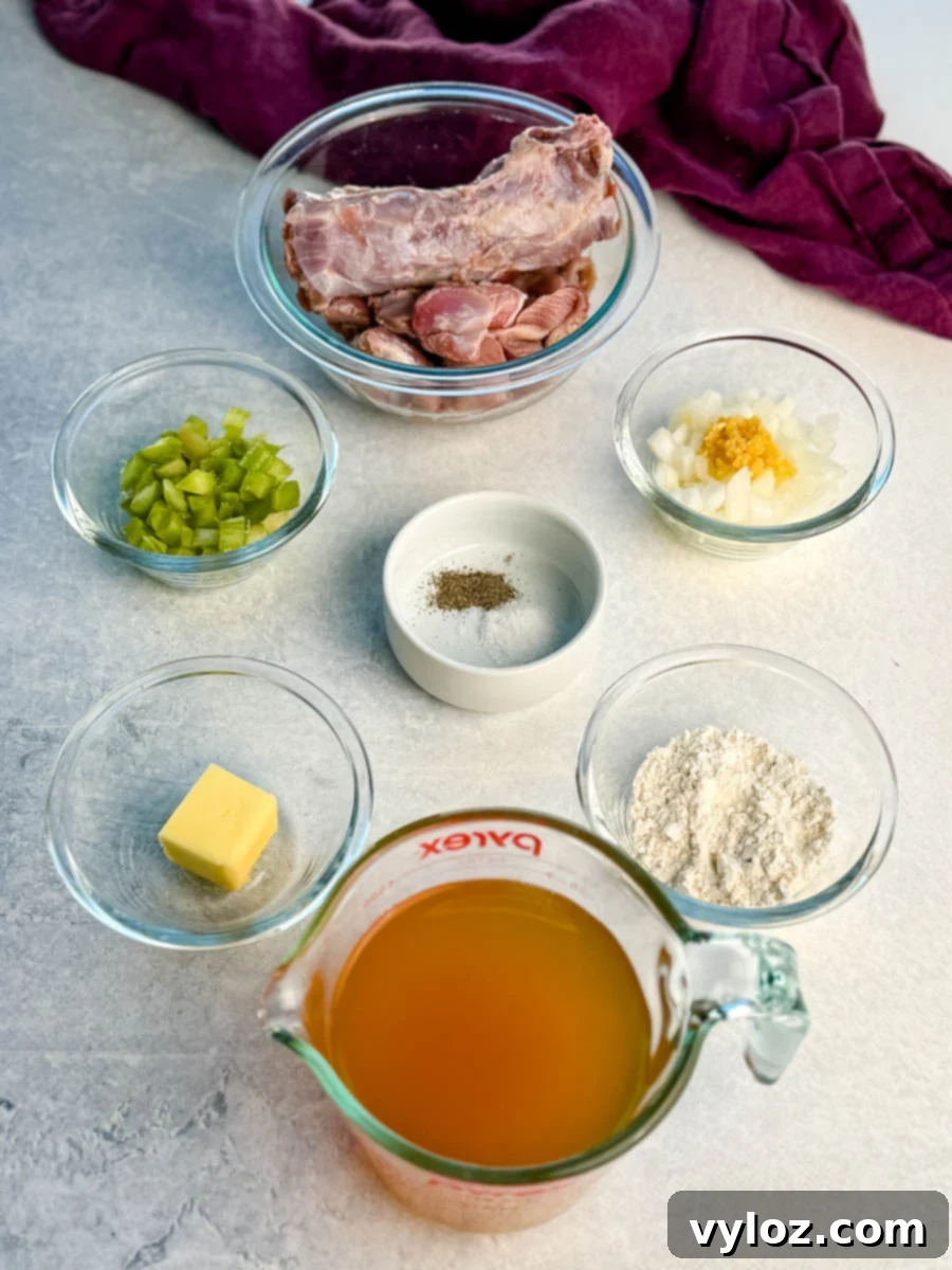 Overhead view of measured ingredients for homemade turkey giblet gravy, including raw turkey neck and giblets in a glass bowl, chopped celery, diced onions with garlic, butter, flour, chicken broth in a measuring cup, and small bowls of salt and black pepper, all arranged neatly on a light countertop with a purple cloth in the background.