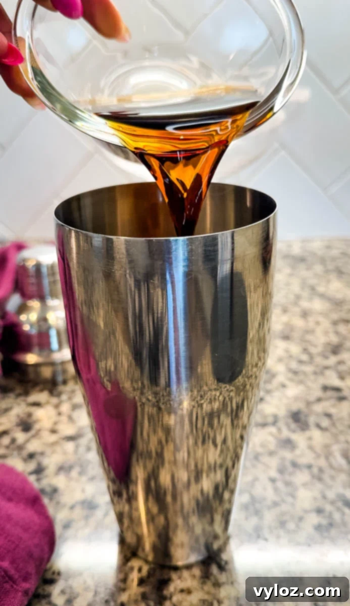 Close-up of coffee being poured into a stainless steel cocktail shaker.