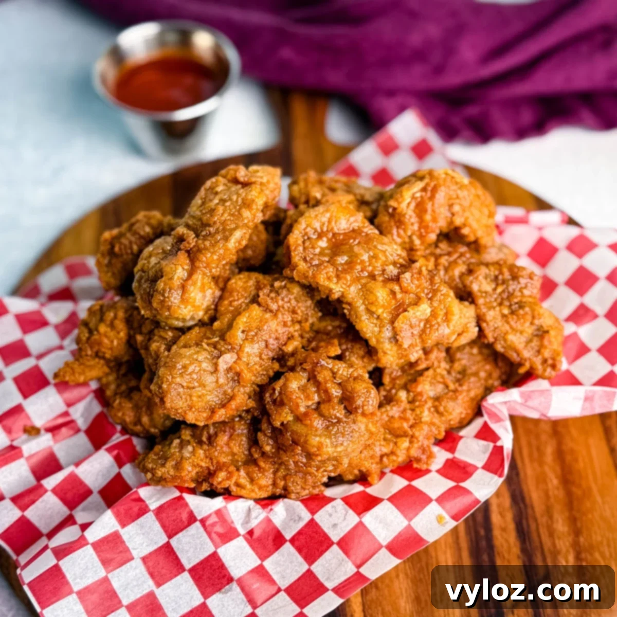Overhead view of a basket of fried chicken gizzards with dipping sauce in the background.