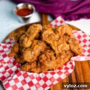 Overhead view of a basket of fried chicken gizzards with dipping sauce in the background.