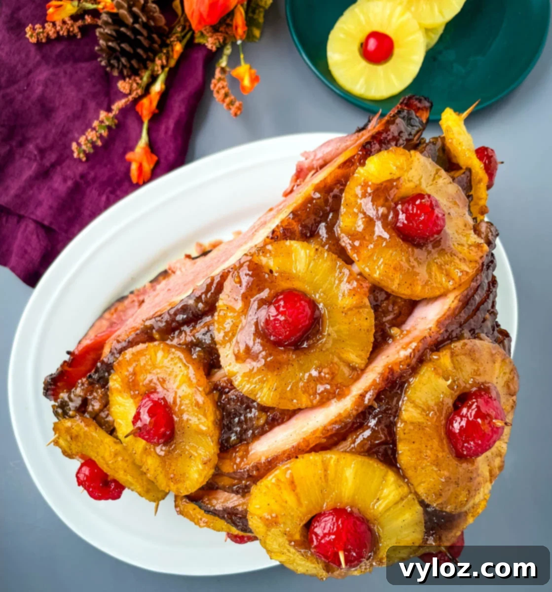 Pineapple glazed ham with cherries on a white plate