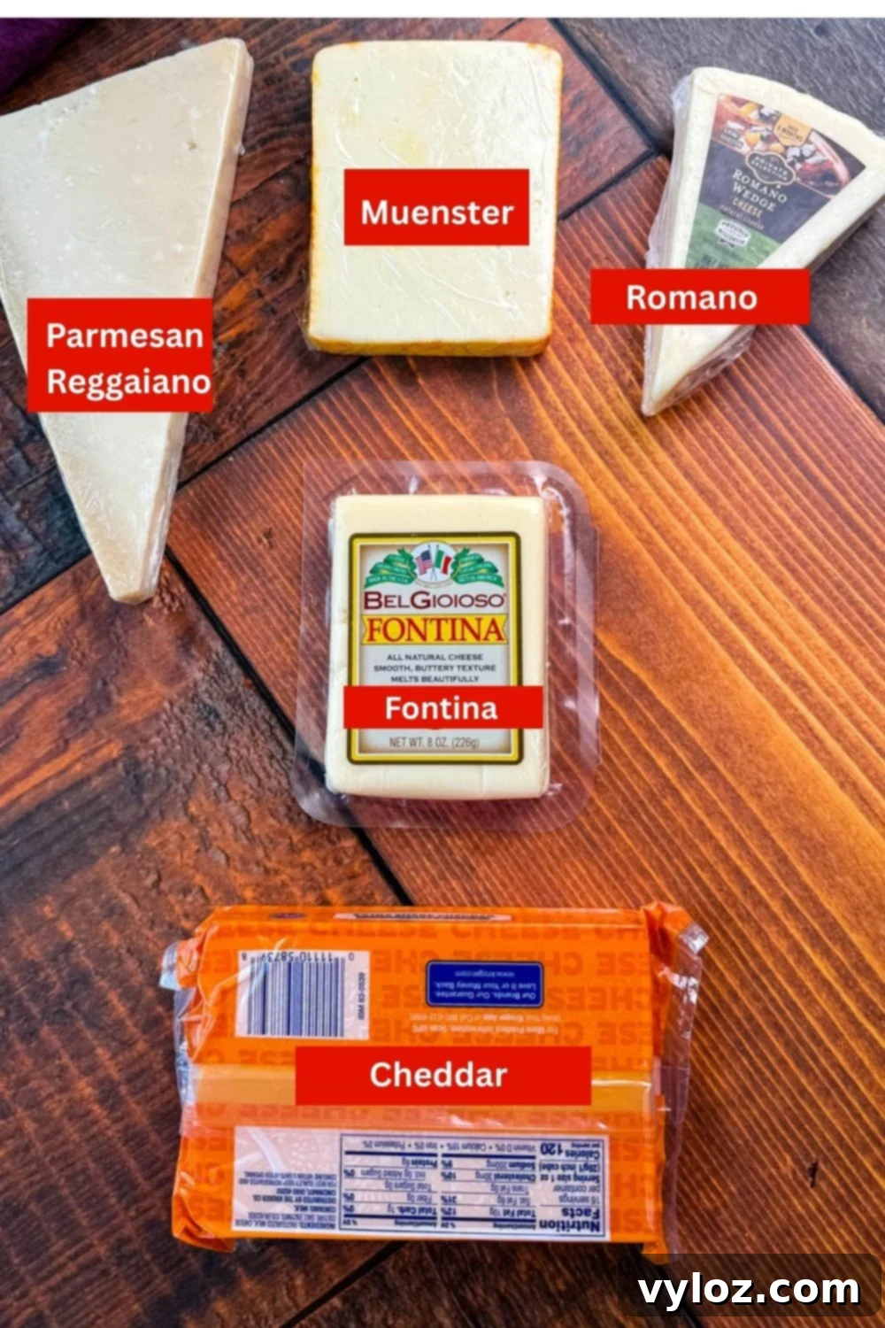 Soulful Golden Baked Macaroni and Cheese 4 Five different types of cheese displayed on a wooden table: Parmesan wedge, smoked gouda block, Romano wedge, packaged Fontina, and a block of cheddar cheese.